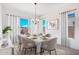 An elegant dining room showcasing a marble table, six chairs, and bright natural light from large windows at 16994 W Canterbury Dr, Surprise, AZ 85388