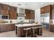 A modern kitchen featuring wooden cabinetry, stainless steel appliances, and a white countertop island with barstool seating at 16994 W Canterbury Dr, Surprise, AZ 85388