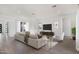 A brightly lit living room featuring contemporary decor, a white sofa, accent chair, and a large television at 16994 W Canterbury Dr, Surprise, AZ 85388