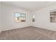 A carpeted bedroom with windows showing the neighborhood views at 11942 W Parkway Ln, Avondale, AZ 85323