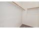 Walk-in closet showcasing a minimalist design with wooden clothing rods and ample storage space at 11942 W Parkway Ln, Avondale, AZ 85323
