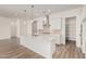 Modern white kitchen with stainless steel range hood, spacious island, pendant lights, and large pantry at 11942 W Parkway Ln, Avondale, AZ 85323