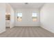 Light-filled bedroom with neutral carpet, two windows, and access to an ensuite bathroom at 11934 W Parkway Ln, Avondale, AZ 85323