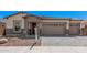Inviting front exterior with a three-car garage, brick accents, and mature desert landscaping at 12007 W Parkway Ln, Avondale, AZ 85323