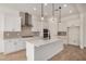 Modern kitchen with white cabinetry, stainless steel appliances, a stylish range hood, and a large island at 12015 W Parkway Ln, Avondale, AZ 85323