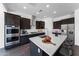 Modern kitchen boasts stainless steel appliances, dark wood cabinets, and a large center island with white countertop at 8722 W Denton Ln, Glendale, AZ 85305