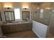 Bathroom featuring double sinks with granite countertops, wood cabinets, and a frameless glass shower at 21369 W Hillcrest Blvd, Buckeye, AZ 85396