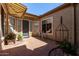 Charming patio with awning, stone flooring, and beautiful potted plants creating a cozy outdoor space at 26747 N 127Th Dr, Peoria, AZ 85383