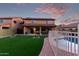 Spacious backyard featuring artificial grass, pool with metal fence, covered patio, and solar panels on roof at 14244 W Indianola Ave, Goodyear, AZ 85395