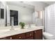 Well-lit bathroom with double sinks, a large mirror, and a shower featuring a glass door at 14244 W Indianola Ave, Goodyear, AZ 85395