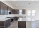 Modern kitchen with dark cabinetry, quartz countertops, and stainless steel appliances at 17993 W Long Lake Rd, Goodyear, AZ 85338