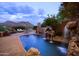 Beautiful backyard pool with rock waterfall feature, landscaping and mountain views at 7702 N Moonlight Ln, Paradise Valley, AZ 85253