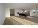 Spacious living room with wood-look tile flooring, opening into kitchen with black and white cabinets at 32535 N 135Th Dr, Peoria, AZ 85383