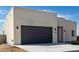 Contemporary home featuring a large gray garage door and modern lighting against a bright stucco facade at 22205 W Ocupado Dr, Wittmann, AZ 85361