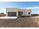 Modern single-Gathering home, featuring a two-car garage, minimalist design, and a xeriscaped front yard under blue sky at 22205 W Ocupado Dr, Wittmann, AZ 85361