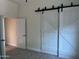 Spacious bedroom featuring barn doors and neutral carpeting at 1187 E Tonto Dr, Chandler, AZ 85249