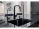 Close up on a kitchen sink with black and gold faucet fixture and black countertop at 12651 S 71St St, Tempe, AZ 85287