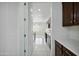 Hallway into kitchen with stainless steel appliances, white countertops, and dark wood cabinets at 19591 W Lincoln St, Buckeye, AZ 85326