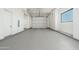 Clean garage with a large roll up door, white walls, and light gray epoxy flooring at 3518 N Shadow Trl, Mesa, AZ 85207
