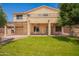 Expansive backyard with a covered patio, balcony, lush green lawn, and mature landscaping providing privacy and relaxation at 15115 W Cottonwood St, Surprise, AZ 85374