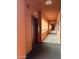 View of a long orange condo hallway with an elevator and view of the outside at 12212 N Paradise Village Pkwy # 203, Phoenix, AZ 85032