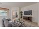 Cozy living room features grey sofa, coffee table, TV console, and large window at 19661 N Echo Rim Dr, Surprise, AZ 85387