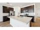 A modern kitchen with stainless steel appliances, dark cabinets, and a large island with a quartz countertop at 4244 E Bradford Ave, San Tan Valley, AZ 85140