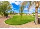 A beautifully landscaped backyard featuring a lush green lawn, gravel paths, and desert foliage at 5312 N Sierra Hermosa Ct, Litchfield Park, AZ 85340