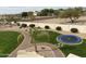 Large backyard with lush grass, palm trees, a fire pit, trampoline, and desert landscaping at 5312 N Sierra Hermosa Ct, Litchfield Park, AZ 85340