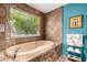 Relaxing bathtub with a large window overlooking bamboo, set against earth-toned tile and blue walls at 8101 N Central Ave # 6, Phoenix, AZ 85020