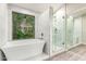 Bright bathroom featuring a soaking tub, glass shower, and large window with a peaceful outdoor view at 3327 S Felix Way, Chandler, AZ 85248