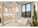 Bright bathroom showcasing a soaking tub by a window and a separate glass-enclosed shower with marble accents at 36323 N 100Th Way, Scottsdale, AZ 85262