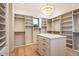 Spacious walk-in closet with custom shelving, drawers, and an island, illuminated by a modern chandelier at 36323 N 100Th Way, Scottsdale, AZ 85262