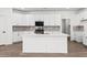 Modern kitchen with white cabinetry, tile backsplash, and central island at 18180 W Pima St, Goodyear, AZ 85338