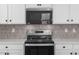 Well-equipped kitchen with stainless steel appliances, tiled backsplash, and modern white cabinetry at 18180 W Pima St, Goodyear, AZ 85338