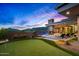 Backyard with a putting green, pool, outdoor fireplace, covered patio, and desert mountain views at sunset at 40575 N 109Th Pl, Scottsdale, AZ 85262