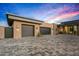 Spacious three-car garage and contemporary home featuring a paved driveway and landscaped yard under a vibrant evening sky at 40575 N 109Th Pl, Scottsdale, AZ 85262