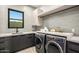 Modern laundry room featuring gray cabinets, stylish countertop, and high-end washer and dryer at 40575 N 109Th Pl, Scottsdale, AZ 85262