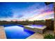 Stunning pool and spa combination featuring tiled accents and vibrant blue lighting against a colorful twilight sky at 40575 N 109Th Pl, Scottsdale, AZ 85262