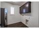 Laundry room with wood-look floors, cabinets, and window with shutters at 7088 W Redbird Rd, Peoria, AZ 85383