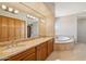 Bright bathroom features double sinks with granite countertops, a soaking tub, and wood cabinets at 9853 E Sundance Trl, Scottsdale, AZ 85262