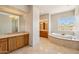 Luxurious main bathroom with dual vanity, marble finishes, and a jetted tub with a view at 9853 E Sundance Trl, Scottsdale, AZ 85262