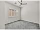 This bedroom features a ceiling fan, large window, neutral paint, and gray carpeting at 13055 W Eagle Talon Trl, Peoria, AZ 85383