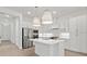 Modern white kitchen with stainless steel appliances, a kitchen island, stylish pendant lighting, and light wood flooring at 20306 W Turney Ave, Buckeye, AZ 85396