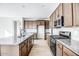 Modern kitchen with granite countertops, dark wood cabinets, and stainless steel appliances at 14927 N 55Th Dr, Glendale, AZ 85306