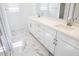 Bright bathroom with double sinks, white cabinetry, and marble-patterned tile flooring at 2428 W Rowel Rd, Phoenix, AZ 85085