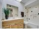 Bright bathroom featuring a wood vanity, mirror, and shower/tub combination with tiled walls at 10619 W Clair Dr, Sun City, AZ 85351