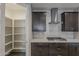 Open kitchen view with a walk-in pantry, dark cabinets, stainless hood and a gas cooktop at 31969 N 117Th Ave, Peoria, AZ 85383