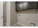 Laundry room with upper storage cabinets and tile floors, next to a white door at 31969 N 117Th Ave, Peoria, AZ 85383