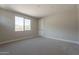 Bright, carpeted bedroom with a large window providing natural light and backyard views at 31985 N 117Th Ave, Peoria, AZ 85383